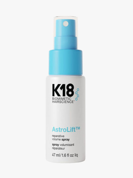 White spray bottle of K18 Biomimetic Hairscience AstroLift Reparative Volume Spray with blue cap on light gray background